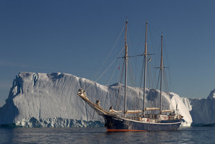 Greenland Sailing Ship dwarfed by Iceberg