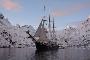 Tallship at anchor surrounded by mountains of Arctic Norway